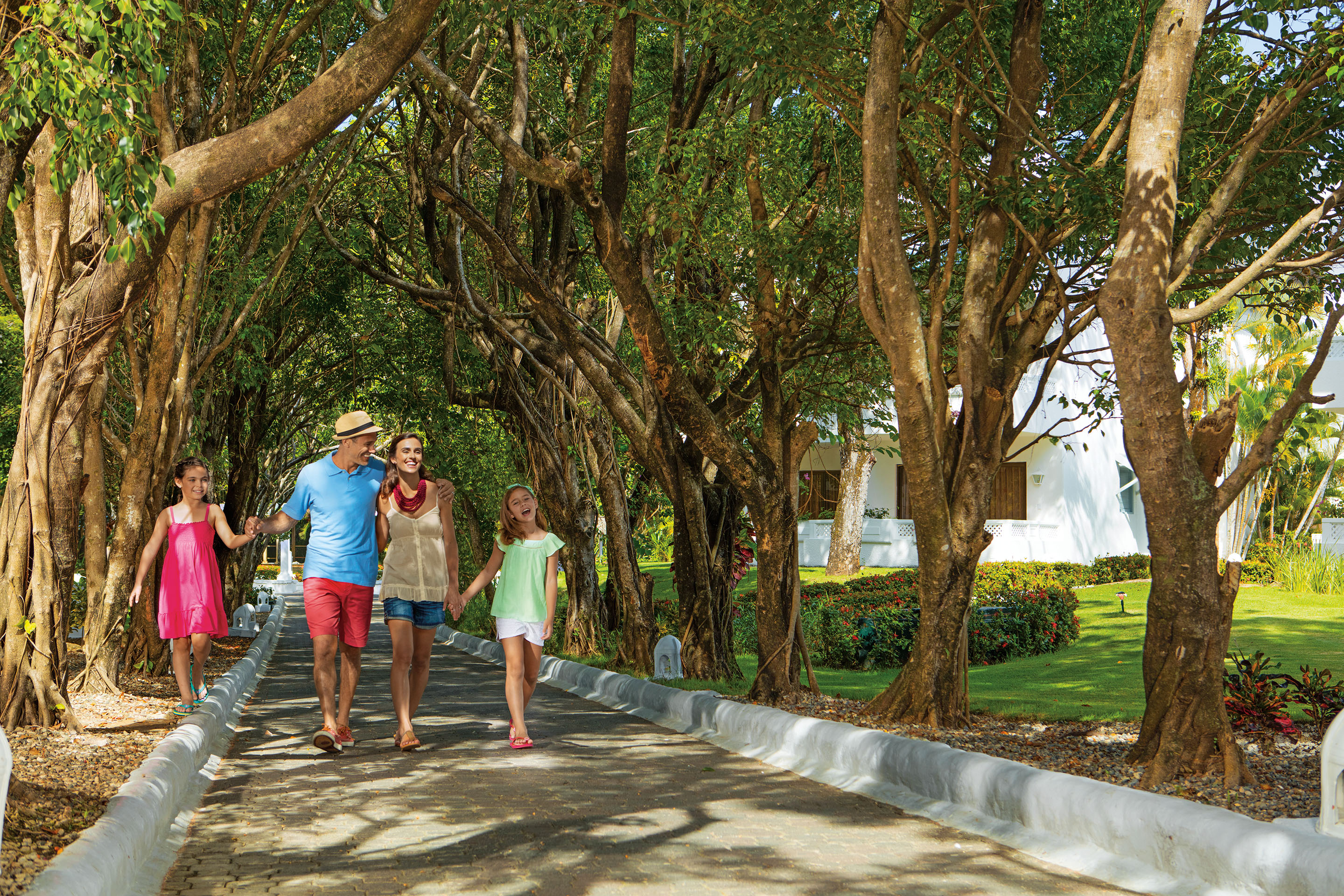 Parents and two daughters walking along path lined with trees